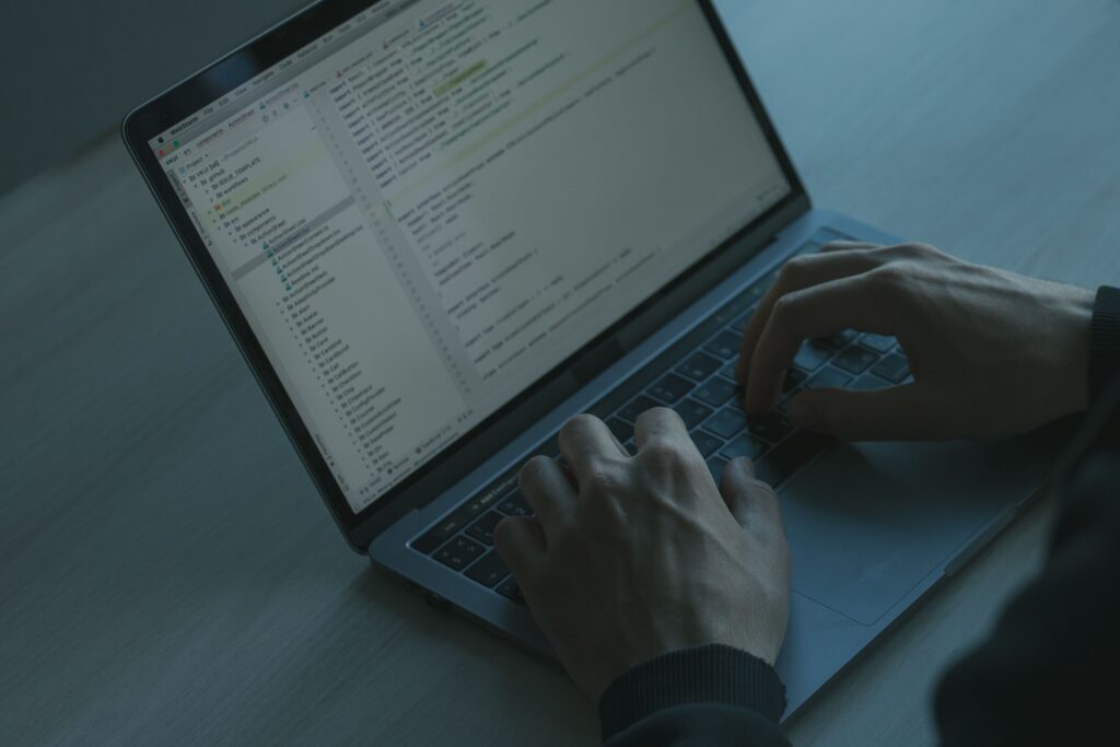 Hands typing code on a laptop