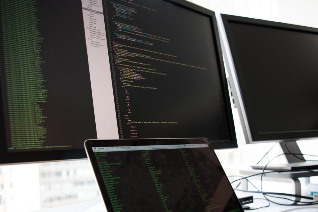 Developer working at a laptop with code displayed on dual monitors